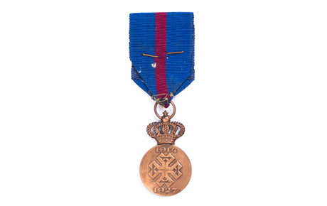 Medalia ”Ferdinand I. Rege al Românilor”, cu spade, cu crucea comemorativă a războiului 1914-1927, acordată lui Delean Valeriu. Decorație, bronz, textil, Ltotală: 11 cm, D: 5 cm. Donație, Aurora Olariu, p.v. nr. 582/26.03.1983.